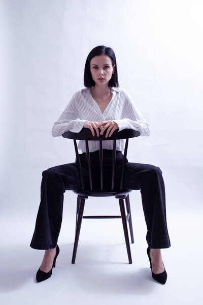 穿着白衬衫和黑裤子的女人坐在椅子上 图片素材