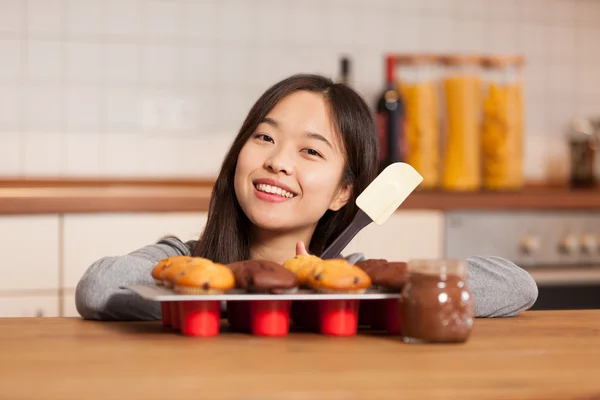 亚洲女人在厨房与纸盒已满的松饼 图片素材