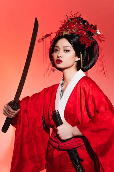 身穿东方服装的日本妇女，身穿红色背景的鞘和剑  图片素材
