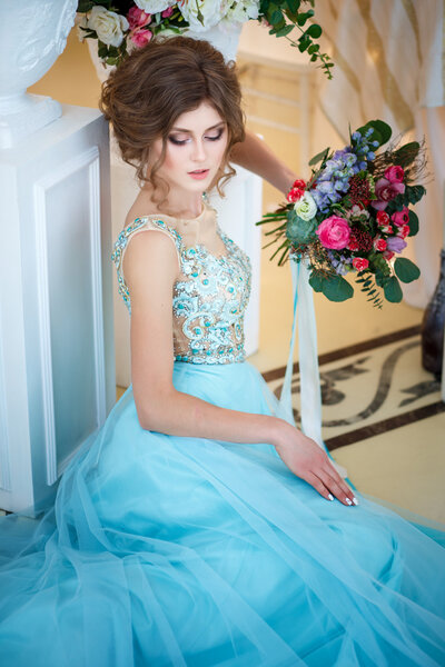 美丽的小姐在奢华的蓝色穿着优雅的室内，用一束鲜花 图片素材