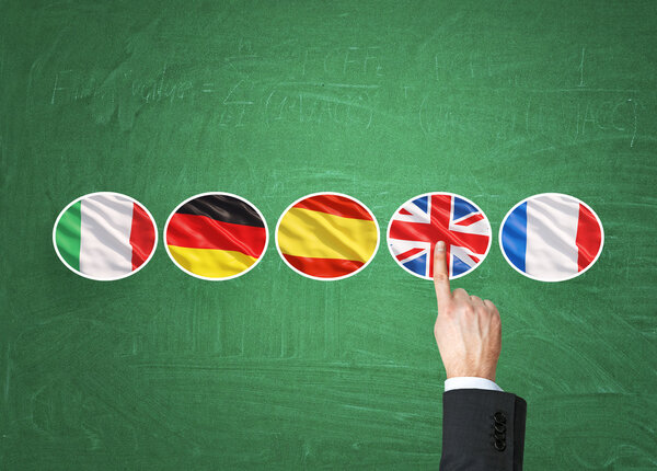 A concept of foreign language studying process. A finger is pointing out the Unites Kingdom flag as a priority in choice of foreign languages. Green chalkboard background. 图片素材