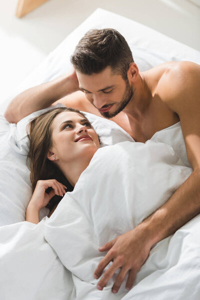 微笑的年轻人拥抱女朋友从后面在床在早晨 图片素材