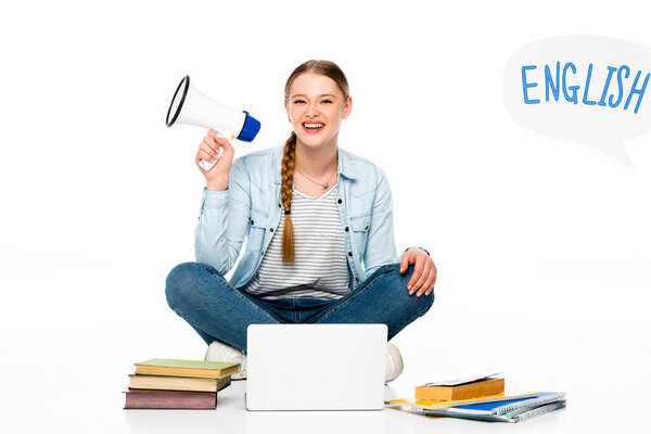 笑着的女孩坐在地板上，带着扩音器靠近笔记本电脑、书本和复印机，英语中的字母出现在白色的泡沫中 图片素材