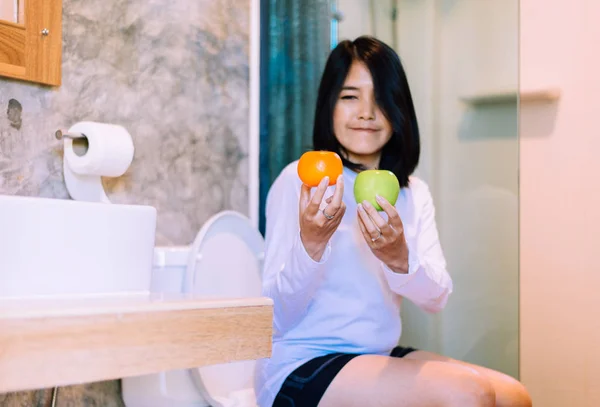 快乐的亚洲女人手捧着橙子，苹果水果当早餐，非常好的系统理念 图片素材