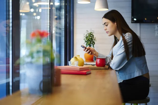 时髦的女孩与短毛坐在时髦的咖啡店和在线聊天的现代智能手机设备连接到免费的4g 互联网。穿着休闲装手机的年轻女子 图片素材