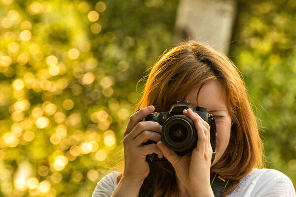 女摄影师拍照背景下的绿叶。前视图 图片素材