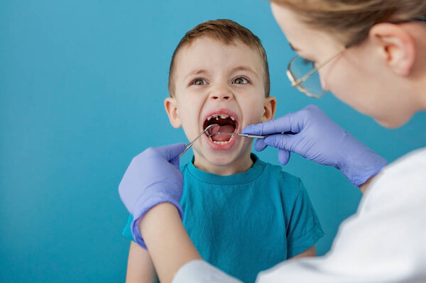 一名身穿蓝色制服的牙医在口腔学镜子的帮助下，对小女孩的口腔和牙齿状况进行检查.正版图库-素材下载-图蜗创意图片库
