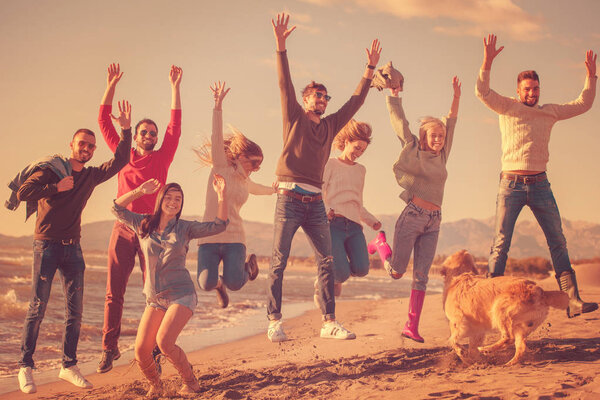 一群兴奋的年轻朋友在阳光灿烂的秋天海滩共舞 图片素材
