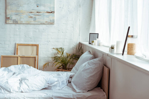 现代化的卧室配有舒适的床、枕头、毯子、图片和植物  图片素材