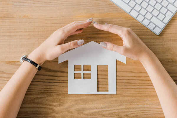 女实业家对木桌上的房子纸模型的部分看法用手, 保险概念 图片素材