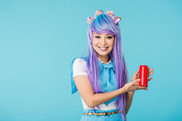 微笑的亚洲动漫女孩在假发举行罐与饮料隔离在蓝色 图片素材