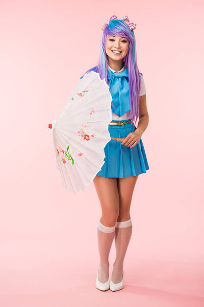 微笑的亚洲动漫女孩拿着纸伞在粉红色全长视图 图片素材
