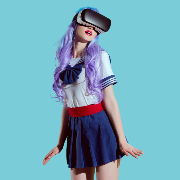时尚女孩在明亮的假发使用虚拟现实耳机蓝色隔离 图片素材