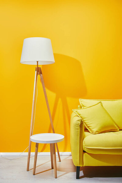 沙发, 配有枕头、落地灯和靠近黄色墙壁的咖啡桌 图片素材
