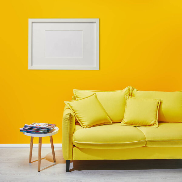 咖啡桌站在现代黄色沙发附近白色框架挂在墙上 图片素材