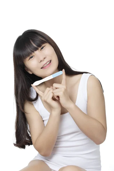 亚洲妇女持有早期怀孕测试仪隔离在白巴 图片素材