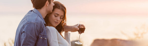 日落时分，男人在海滩上举杯时拥抱女人的网站首页  图片素材