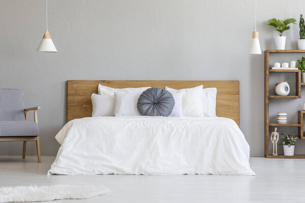 蓝色枕头在白色床与木床头板在卧室内部与扶手椅。真实照片 图片素材